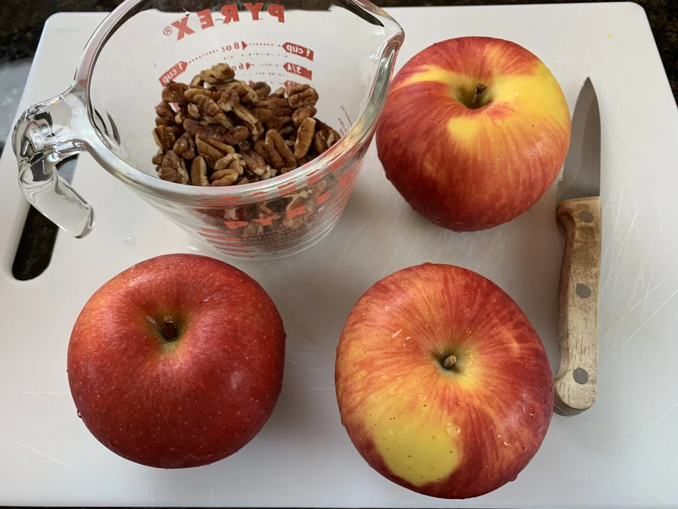 Apples, nuts and knife on cutting board
