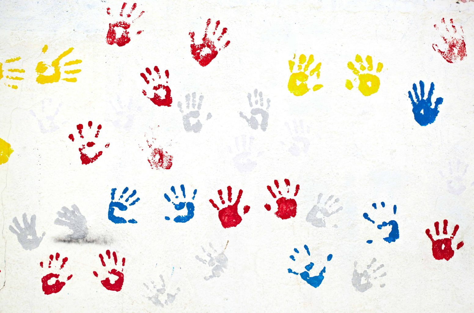 Graffiti with multiple colored hand prints on the white wall 